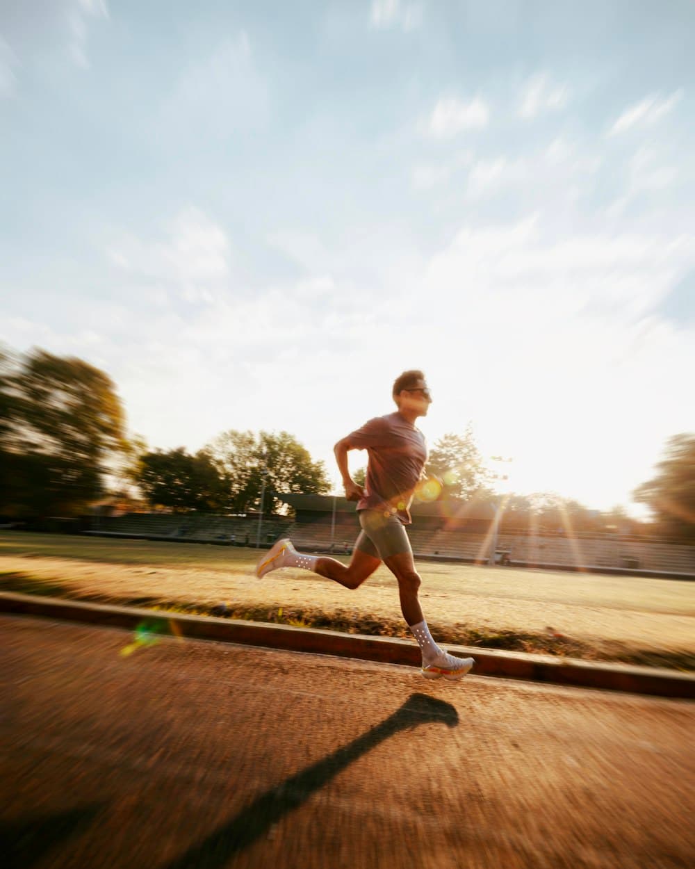 A man running on a track at sunrise