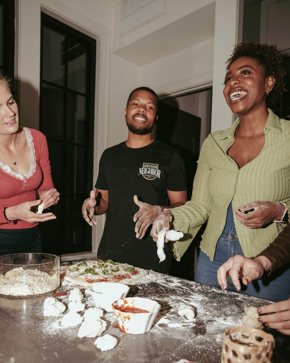 Friends making pizza together at a kitchen counter
